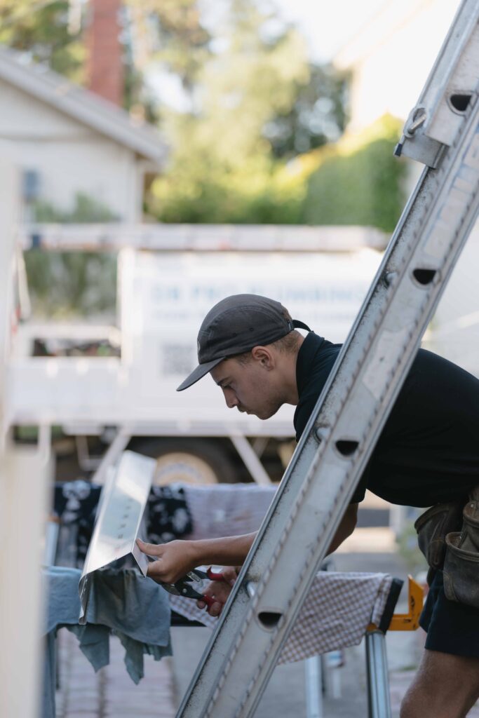 A worker concentrates while cutting a piece of metal. DB Pro Plumbing.